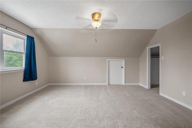 bonus room featuring a textured ceiling, carpet flooring, baseboards, and lofted ceiling