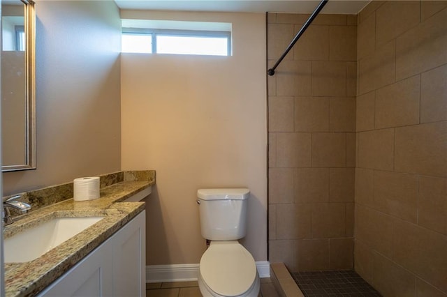 full bath featuring vanity, baseboards, a tile shower, and toilet