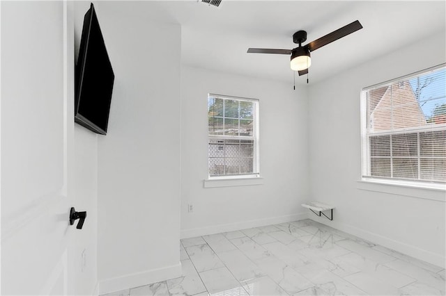 empty room featuring baseboards, marble finish floor, and ceiling fan
