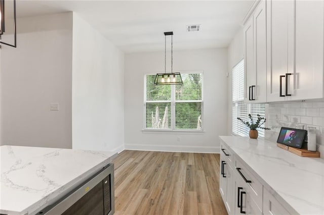 185 Boutte Estates Dr, Boutte, LA 70039 - kitchen featuring white cabinets, baseboards, light wood-style floors, and decorative backsplash