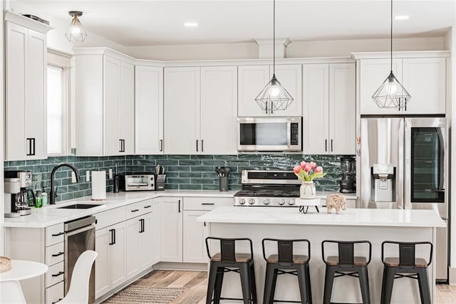 41820 S Genois St, New Orleans, LA 70119 - kitchen featuring white cabinets, a sink, appliances with stainless steel finishes, a breakfast bar, and a kitchen island