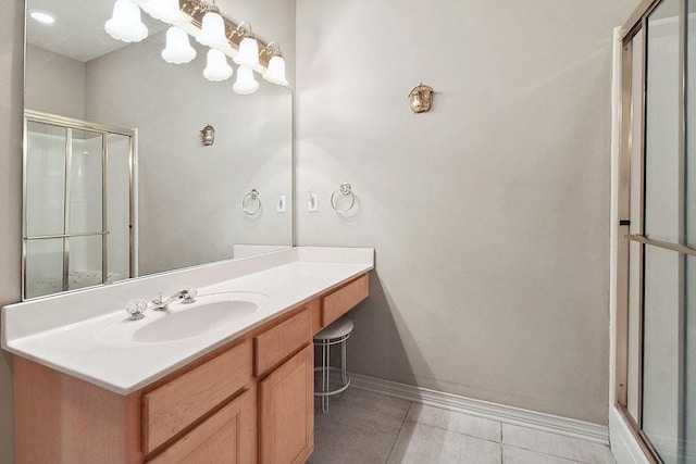 full bath with tile patterned floors, vanity, baseboards, and a shower with door