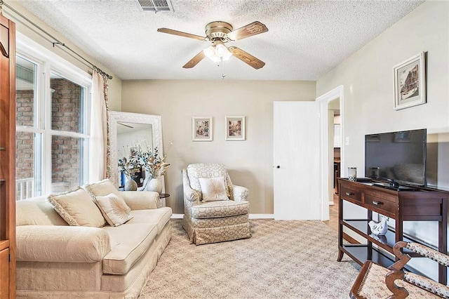 living room with carpet floors, visible vents, ceiling fan, and a textured ceiling