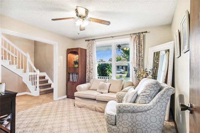 living room with tile patterned floors, a textured ceiling, baseboards, ceiling fan, and stairs