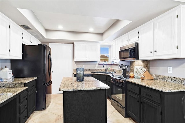 kitchen featuring a tray ceiling, visible vents, a sink, black appliances, and white cabinets
