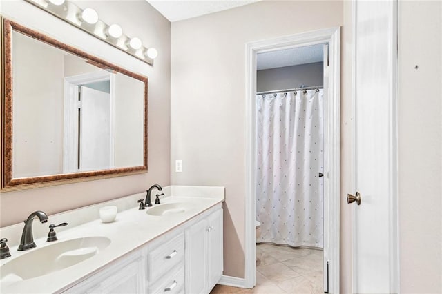 bathroom with double vanity, toilet, curtained shower, and a sink