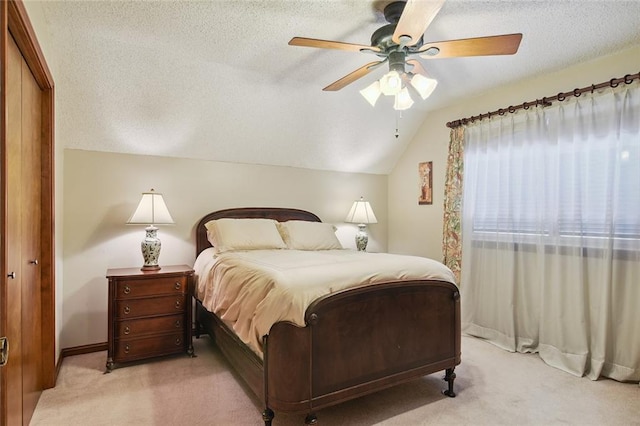 bedroom with lofted ceiling, a textured ceiling, ceiling fan, and light colored carpet