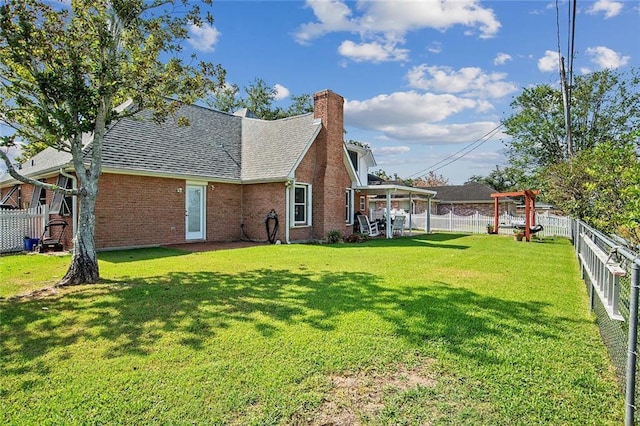 exterior space featuring brick siding, a yard, a chimney, and a fenced backyard