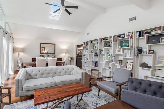 living room featuring visible vents, a ceiling fan, lofted ceiling with skylight, and wood finished floors