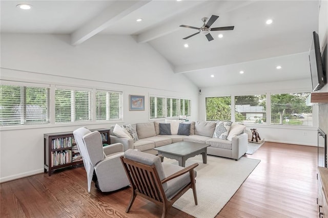 living area featuring vaulted ceiling with beams, wood finished floors, and a healthy amount of sunlight