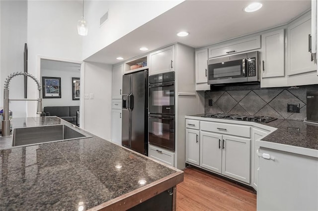 kitchen featuring visible vents, tile countertops, tasteful backsplash, a sink, and black appliances
