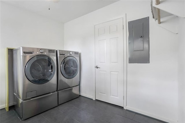 washroom featuring dark tile patterned floors, electric panel, laundry area, baseboards, and washer and clothes dryer