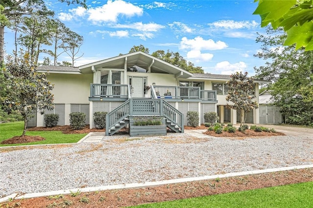 view of front of home featuring stucco siding, covered porch, and stairway