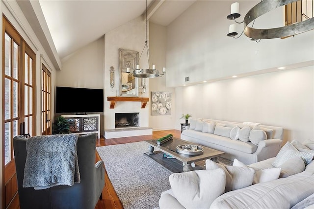 living room with a fireplace, high vaulted ceiling, wood finished floors, beamed ceiling, and visible vents