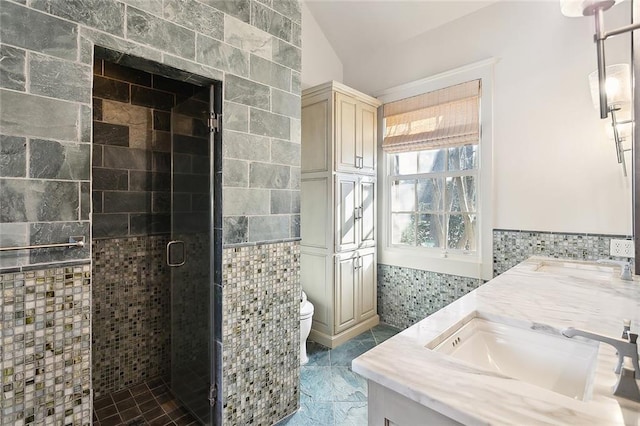 bathroom featuring vanity, toilet, tile walls, a shower stall, and lofted ceiling