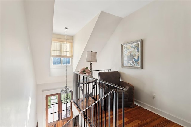 stairway with baseboards, wood finished floors, and a chandelier