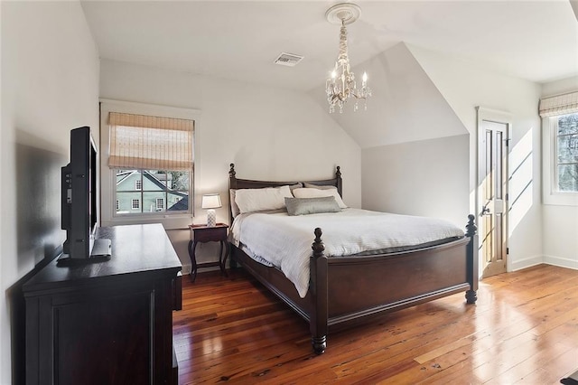 bedroom featuring wood-type flooring, visible vents, an inviting chandelier, baseboards, and vaulted ceiling