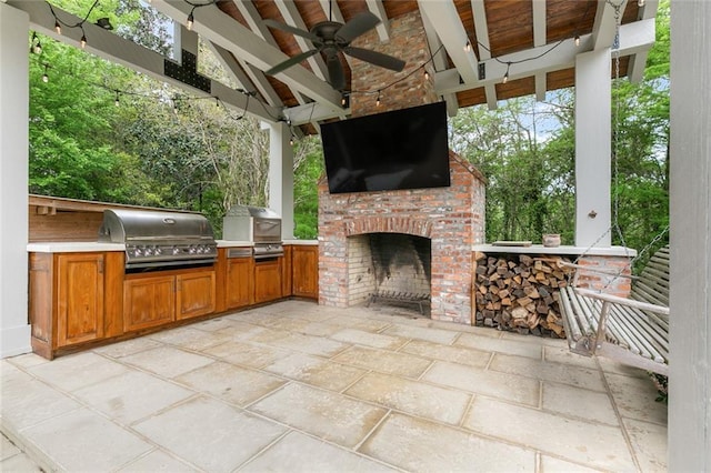 view of patio / terrace with an outdoor brick fireplace, ceiling fan, and area for grilling