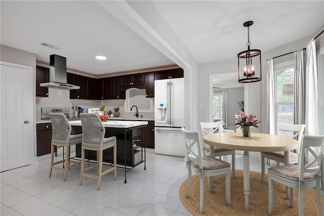21216 Gardenia St, Covington, LA 70435 - kitchen featuring wall chimney range hood, white refrigerator with ice dispenser, stove, light countertops, and a kitchen bar