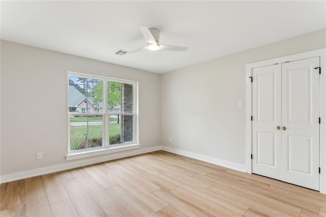 spare room with baseboards, visible vents, ceiling fan, and light wood-type flooring