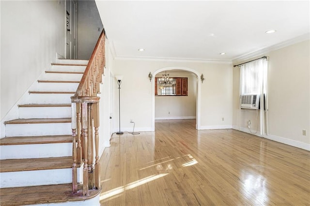 staircase featuring crown molding, baseboards, a chandelier, arched walkways, and wood finished floors