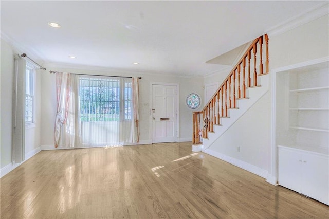 entrance foyer featuring baseboards, wood finished floors, stairway, and crown molding