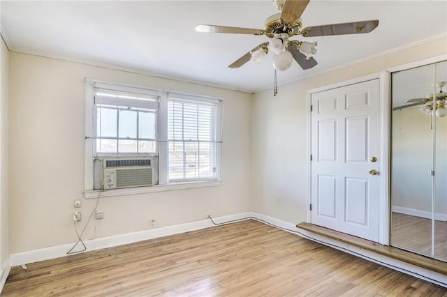 unfurnished bedroom featuring cooling unit, baseboards, a closet, and wood finished floors