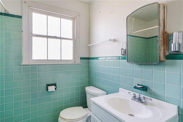 full bathroom with a wainscoted wall, a shower, toilet, vanity, and tile walls