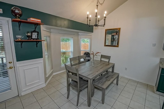dining room with baseboards, an inviting chandelier, light tile patterned floors, and lofted ceiling
