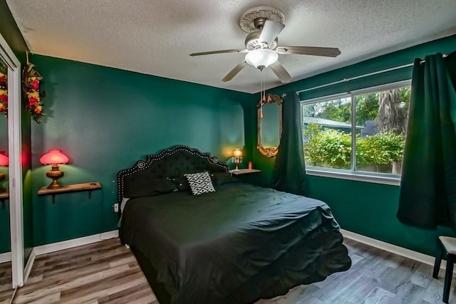 bedroom with baseboards, a textured ceiling, and wood finished floors