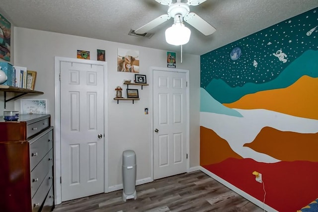 bedroom featuring ceiling fan, a textured ceiling, baseboards, wood finished floors, and visible vents