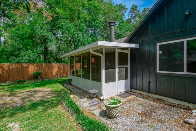 exterior space featuring a lawn, fence, and a sunroom