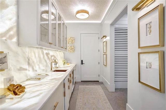 clothes washing area featuring a sink and a textured ceiling