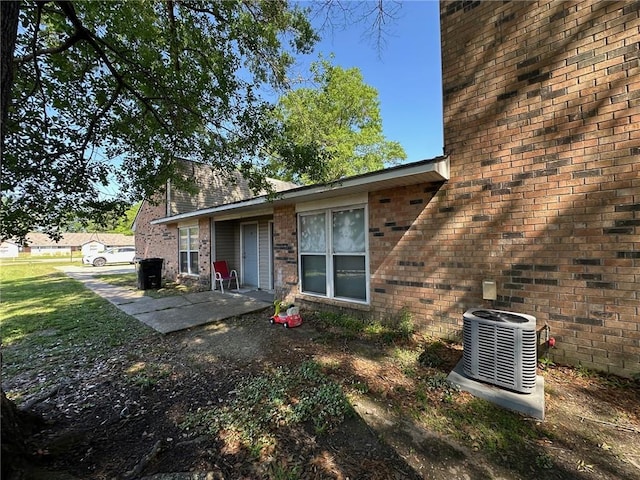 44154 Simpson Pl, Hammond, LA 70403 - view of side of home with central AC unit, brick siding, and a patio