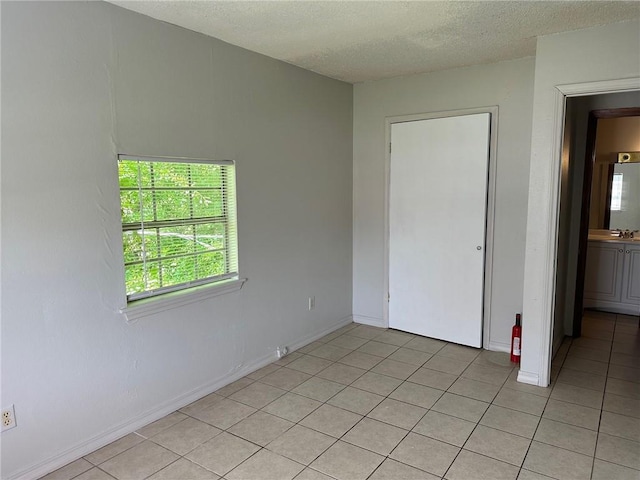 44321 Simpson Pl, Hammond, LA 70403 - unfurnished bedroom featuring baseboards, a sink, a textured ceiling, and light tile patterned floors