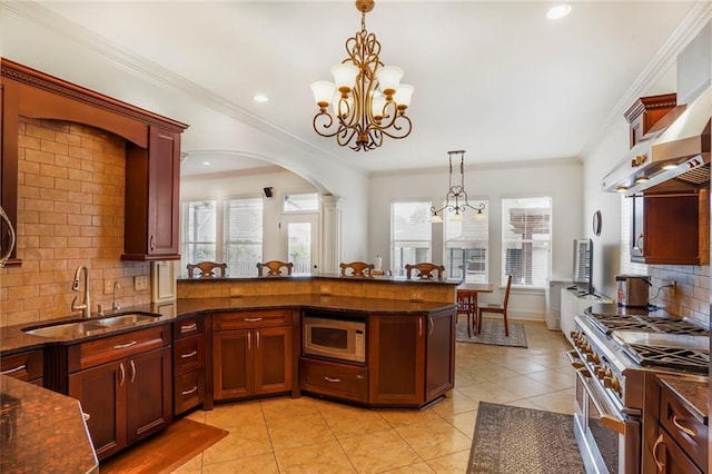6021 W End Blvd, New Orleans, LA 70124 - kitchen with high end stainless steel range oven, white microwave, a chandelier, tasteful backsplash, and decorative light fixtures