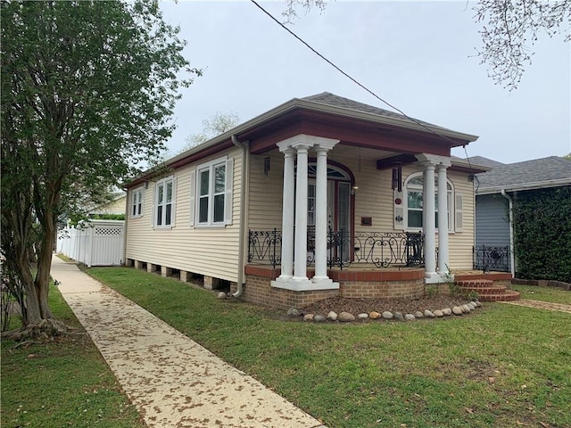 view of front facade featuring a front lawn, covered porch, and fence