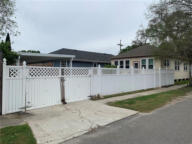 exterior space featuring driveway, a gate, fence, and a shingled roof