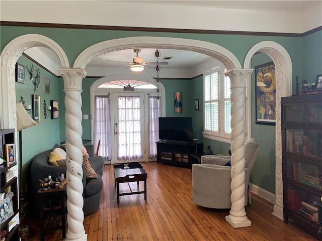living room with hardwood / wood-style floors, arched walkways, ceiling fan, and ornate columns