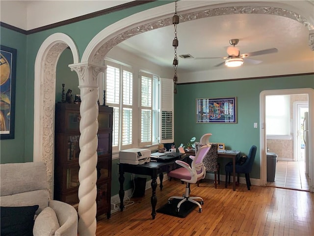 office space with visible vents, baseboards, a ceiling fan, arched walkways, and light wood-type flooring