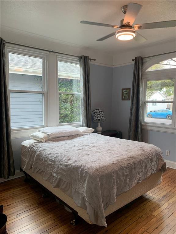 bedroom with hardwood / wood-style flooring, multiple windows, and ceiling fan