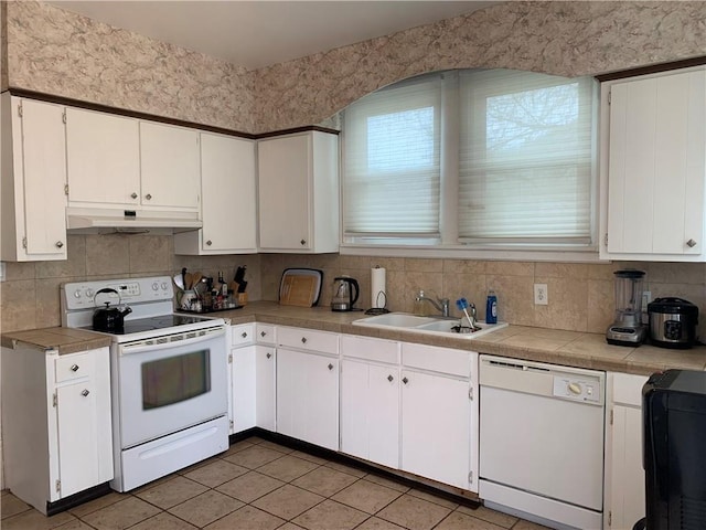 kitchen with white cabinets, a sink, under cabinet range hood, and white appliances