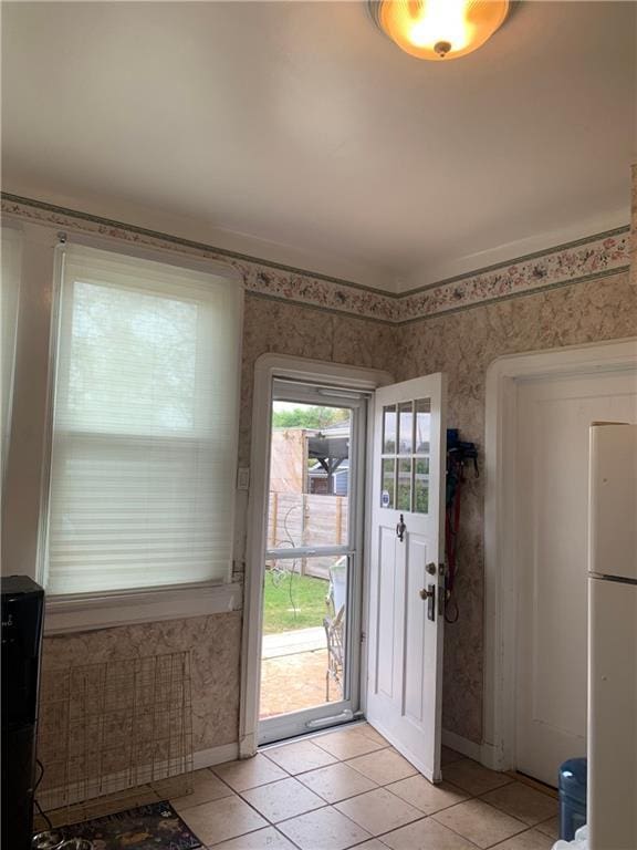 interior space featuring baseboards, wallpapered walls, and light tile patterned floors