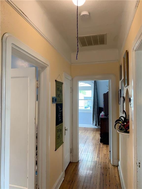 hallway with baseboards, visible vents, and light wood-style flooring