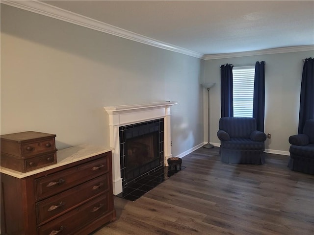 living area with a tiled fireplace, ornamental molding, baseboards, and dark wood-style floors