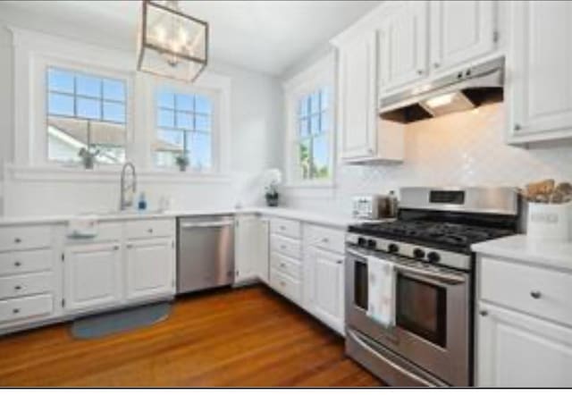 3015 Nashville Ave, New Orleans, LA 70125 - kitchen featuring white cabinets, under cabinet range hood, dark wood-style floors, and appliances with stainless steel finishes
