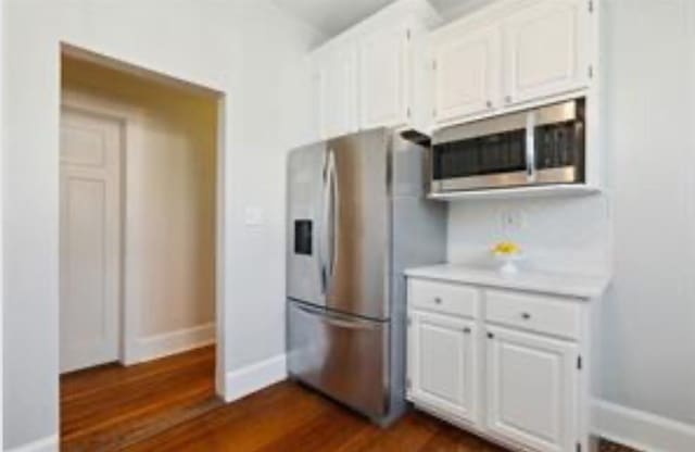 3015 Nashville Ave, New Orleans, LA 70125 - kitchen featuring white cabinetry, light countertops, appliances with stainless steel finishes, and dark wood-type flooring