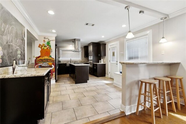 5601 Charlotte Dr, New Orleans, LA 70122 - kitchen featuring visible vents, wall chimney exhaust hood, a center island, and crown molding