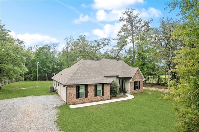 view of front of home featuring fence, gravel driveway, a garage, brick siding, and a front lawn