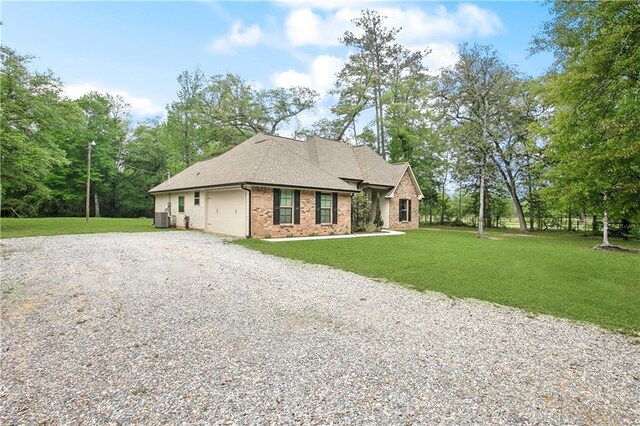 view of front of house featuring a front yard, an attached garage, brick siding, gravel driveway, and central AC